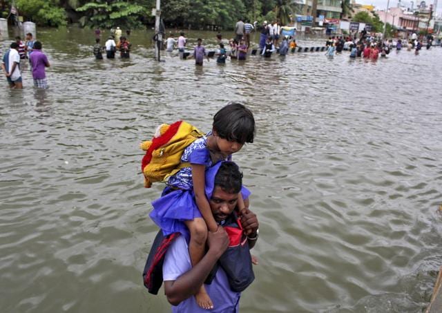 A man carries a girl through a flooded road in Chennai. (REUTERS)
