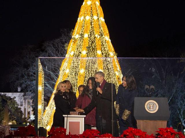 US President Barack Obama and First Lady Michelle Obama light the National Christmas Tree in President's Park outside the White House in Washington, DC, December 3, 2015 with their daughters Malia (C) and Sasha (2nd L), as well as actress Reese Witherspoon (L). (AFP)