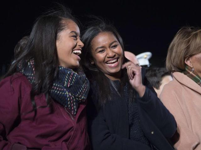 First daughters Malia (L) and Sasha (C) share a laugh on the Ellipse of the National Mall on Thursday. The First Family was joined by celebrities and guests to light the National Christmas tree during an evening of performances. (AFP)