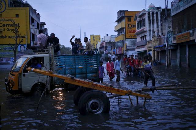 People commute through a flooded street in Chennai. (REUTERS)