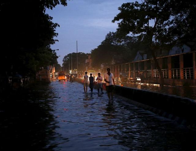 People wade through a flooded road in Chennai. (REUTERS)