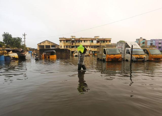 A man carries drinking water in a pitcher through a flooded street in Chennai on December 4, 2015. City residents are struggling to return to normalcy with partial restoration of telecommunication and train services. (REUTERS) A man carries drinking water in a pitcher through a flooded street in Chennai on December 4, 2015. City residents are struggling to return to normalcy with partial restoration of telecommunication and train services. (REUTERS)