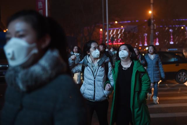 Pedestrians cross a road on a heavily polluted evening in Beijing. (AFP) Pedestrians cross a road on a heavily polluted evening in Beijing. (AFP)