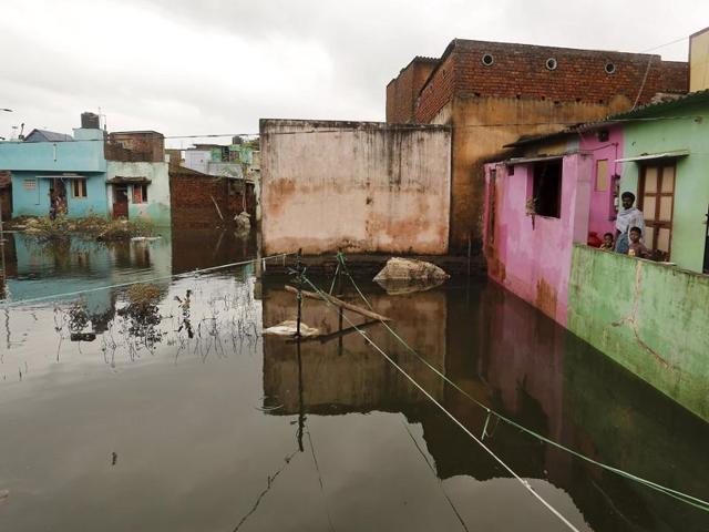A man along with his children stands inside their flooded house in Chennai.(REUTERS)