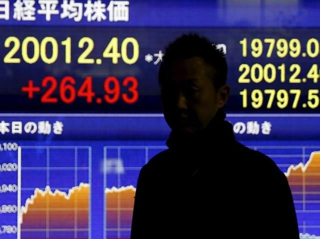 A man stands in front of an electronic board showing Japan's Nikkei average outside a brokerage in Tokyo. The Bank for International Settlements (BIS) issued a warning Sunday over an “uneasy calm” within financial markets, noting that the global economy remains vulnerable to serious disruptions. (REUTERS)