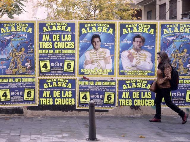 A woman walks past posters announcing a circus with the faces of the leader of Ciudadanos political party Albert Rivera (L) and Spanish Prime Minister and leader of Popular Party (PP) Mariano Rajoy (R).(AFP)