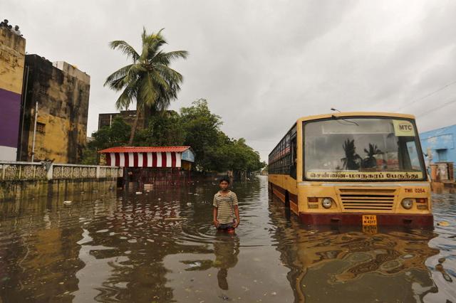 A boy next to a partially submerged bus in a flooded locality in Chennai. (REUTERS) A boy next to a partially submerged bus in a flooded locality in Chennai. (REUTERS)