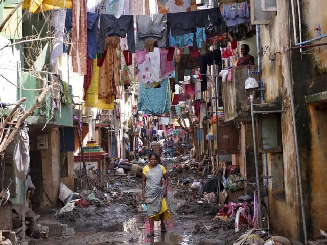A woman walks in an alley filled with mud and debris to collect relief goods as clothes are hung out to dry after flood waters receded in Chennai. (REUTERS Photo)