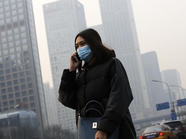A woman, wearing a mask to protect herself from pollutants, walks past office buildings shrouded with pollution haze in Beijing. (AP Photo) A woman, wearing a mask to protect herself from pollutants, walks past office buildings shrouded with pollution haze in Beijing. (AP Photo)