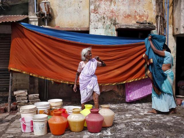 A woman waits outside her house for a water tanker to fill her containers with drinking water in Chennai. (REUTERS Photo)