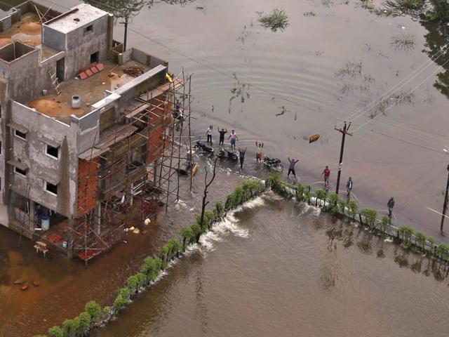 Flood-affected people gesture to an Indian coast guard helicopter for relief materials in Chennai. (REUTERS Photo)