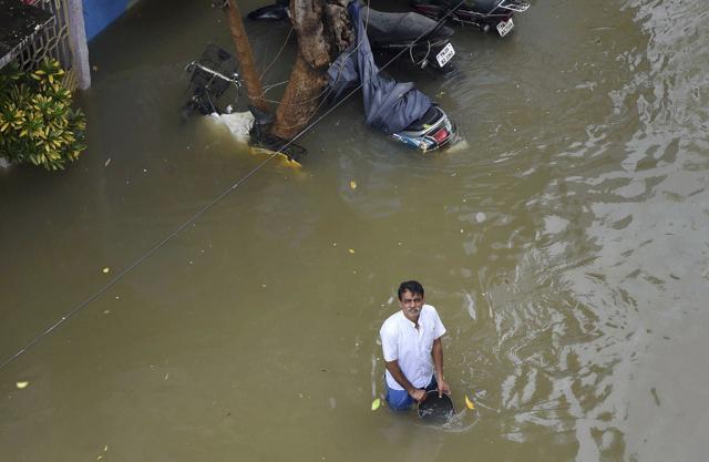 A man waits for food packets in floodwaters following heavy rains in Chennai. (AP) A man waits for food packets in floodwaters following heavy rains in Chennai. (AP)