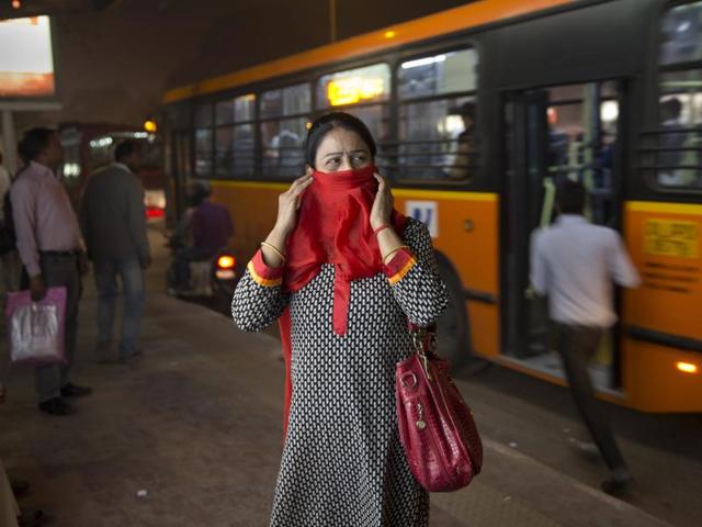 In this November 27, 2015 photo, a woman covers her face from pollution as she waits at a bus station in New Delhi. To discourage private car use, we need to invest in public transport.(AP)