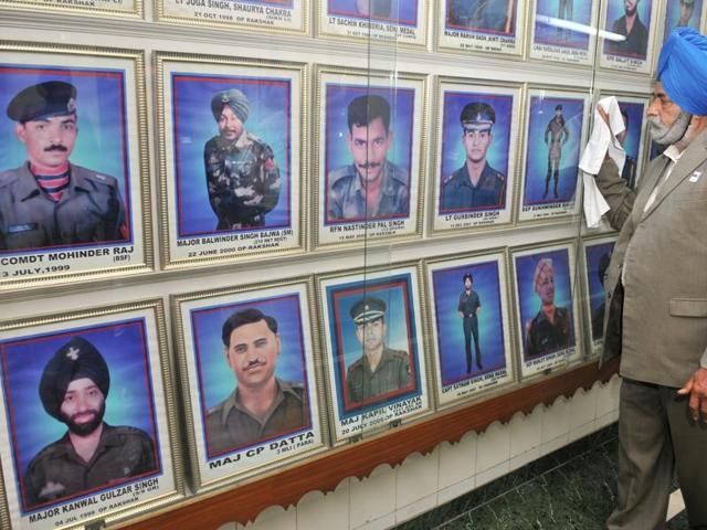 Father of martyr Lt Gurbinder Singh cleaning portraits of the martyrs at the Hall Of Fame at Punjab State War Memorial, Jalandhar. (Pardeep Pandit/HT Photo)