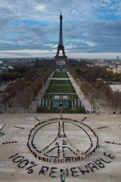 People make the "Pray for Paris" sign along with the slogan "100 percent renewable" near the Eiffel Tower in Paris. (AFP Photo)