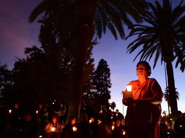 Photographs of victims of the terrorist attack on the Inland Regional Center are seen as people hold candles while attending a vigil held at the San Bernardino County Board of Supervisors headquarters.(Getty images/AFP)