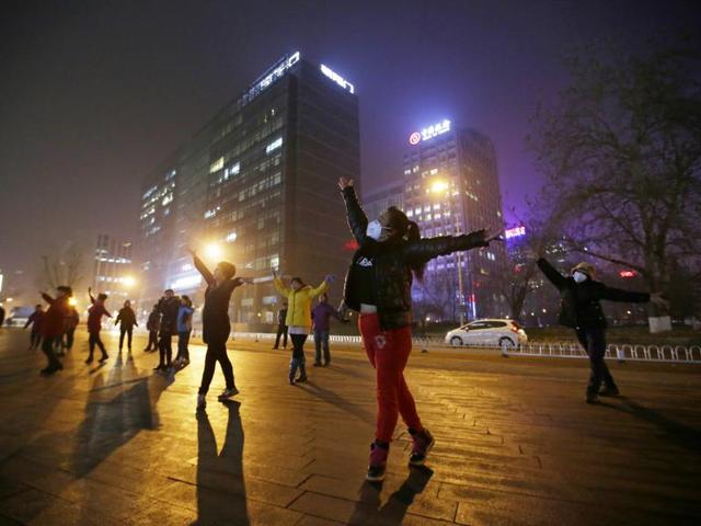 Women wearing masks and other residents dance during their daily exercise amid the heavy smog in Beijing. (REUTERS)