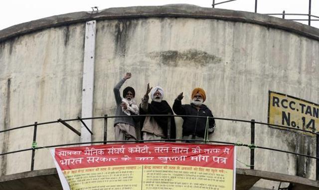 Harbhal Singh, Pargat Singh, Gurdial Singh and Kartar Singh, all residents of Tarn Taran district, remained on the tank for 16 hours, prompting the police to deploy more than two dozen policemen at the spot. (JS Grewal/HT Photo)