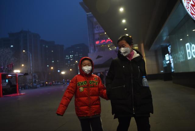 A mother and son wear masks on a polluted day in Beijing on Wednesday. Pollution red alerts spread to more Chinese cities, the state media reported, as Beijing entered its third day of heavy smog. (AFP)