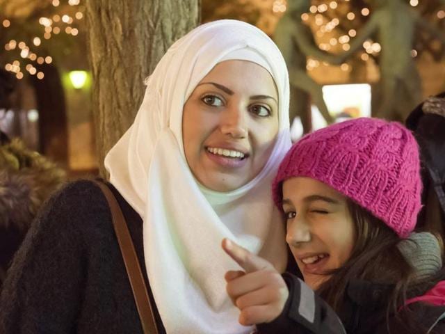 In this photo taken Tuesday, Dec. 8, 2015, Syrian refugee Raghad Habashieh, right, talks with her sister Reem Habashieh, left, as they visit the Christmas market in Zwickau, eastern Germany. (AP Photo) In this photo taken Tuesday, Dec. 8, 2015, Syrian refugee Raghad Habashieh, right, talks with her sister Reem Habashieh, left, as they visit the Christmas market in Zwickau, eastern Germany. (AP Photo)