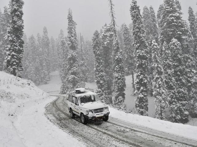 A vehicle drives past a snow covered Gulmarg Tangmarg road about 38 kilometers from Srinagar. (Waseem Andrabi/ HT Photo)