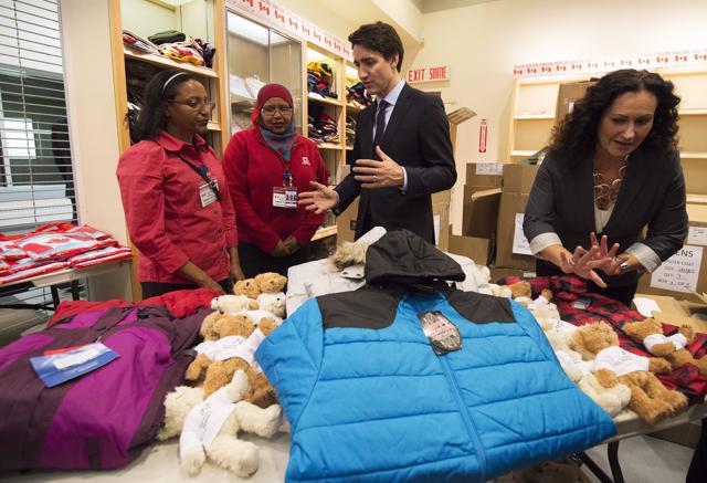 Canadian Prime Minister Justin Trudeau looks over winter clothing which was to be handed out to arriving Syrian refugees before their arrival at the Pearson International airport, in Toronto. (AP Photo)