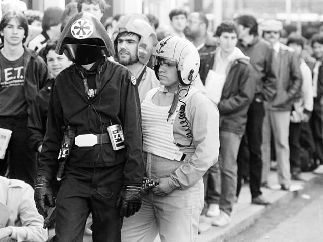 In this May 25, 1983 file photo, three costumed fans of the Star Wars movie trilogy, Kevin Maguire, from left, as an Imperial Fire Control Officer, Stephen Robards, and his brother John Robards as Rebel Fighter Pilots, stand in a line of ticket buyers outside a Boston theatre, before the first showing there of the film Return of the Jedi. The effect Star Wars has had on movies is as colossal as the Death Star itself and to some, just as fearsome. (AP) 