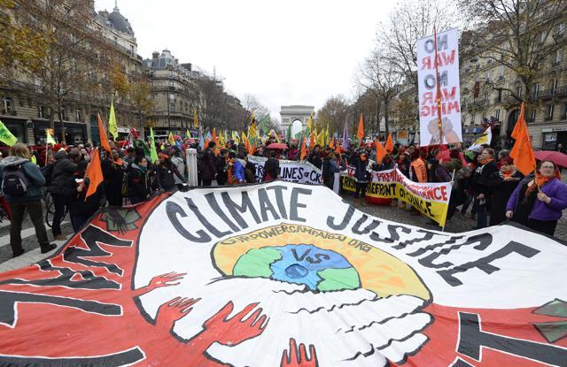 Activists hold up a giant banner reading 'Climate justice' by association 'ourpowercampaign' during a demonstration near the Arc de Triomphe at the Avenue de la Grande armee boulevard in Paris on Saturday. (AFP)