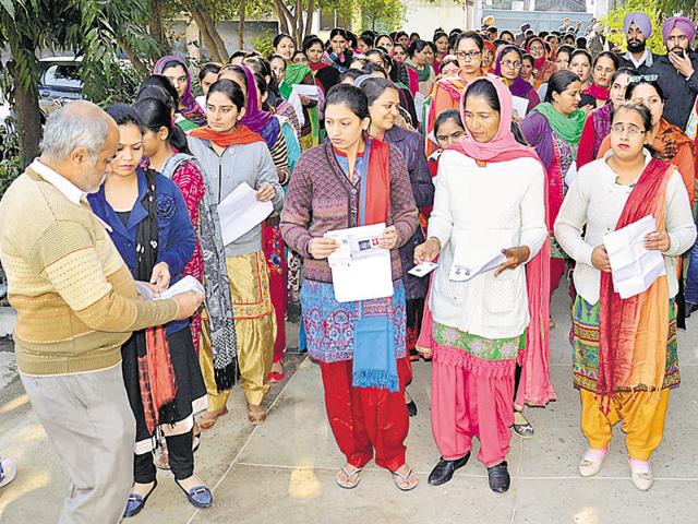 District education officials checking documents of Punjab State Teacher Eligibility Test (PSTET) candidates outside the examination centre in Amritsar on Sunday.(Sameer Sehgal / HT Photo)