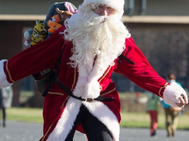 A man dressed in a Santa Claus costume skates along the bike path on the banks of the Elbe River in Dresden, Germany, Sunday December 6, 2015. (AP)