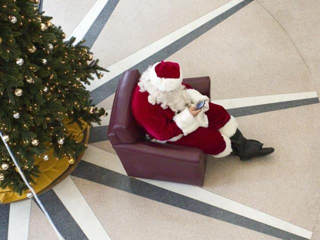 Santa Clause checks his cellphone while waiting for University of Idaho students who want to be photographed with him at the Idaho Commons in Moscow, Idaho, on Wednesday, Dec. 2, 2015. (AP)