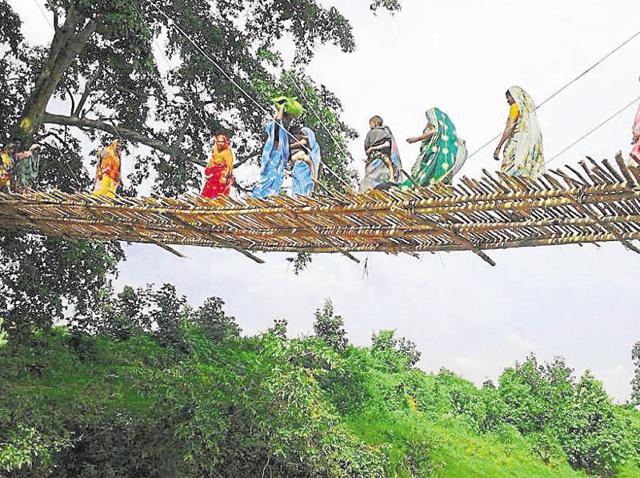 Women cross the bamboo bridge over river Karmanasa, a tributary of the Ganges.(HT Photo)