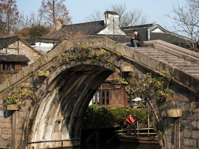 A participant (top) of the World Internet Conference browses the Internet with his smartphone on a bridge in Wuzhen, China. (AFP) A participant (top) of the World Internet Conference browses the Internet with his smartphone on a bridge in Wuzhen, China. (AFP)