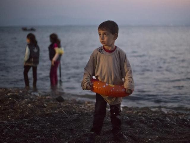 A Syrian migrant boy still wearing a swimming ring stands on the beach upon his arrival with other migrants by a dinghy at the southeastern Greek island of Kos, Greece. (AP) A Syrian migrant boy still wearing a swimming ring stands on the beach upon his arrival with other migrants by a dinghy at the southeastern Greek island of Kos, Greece. (AP)