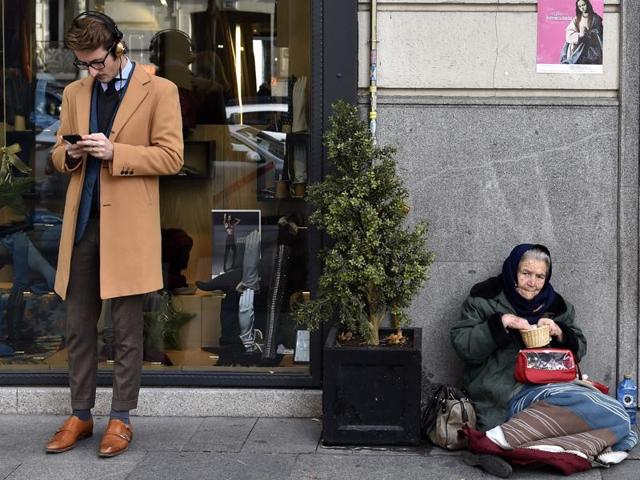 A man consults a mobile phone beside a woman begging on the pavement in Salamanca, an upscale neighbourhood of Madrid. The number of millionaires in Spain rose by 40% to 178,000 last year from 2008 when the crisis started while the number of people living with “severe material deprivation” in the country has doubled since 2007 to just over three million last year, according to a study by anti-poverty agency Oxfam. (AFP) A man consults a mobile phone beside a woman begging on the pavement in Salamanca, an upscale neighbourhood of Madrid. The number of millionaires in Spain rose by 40% to 178,000 last year from 2008 when the crisis started while the number of people living with “severe material deprivation” in the country has doubled since 2007 to just over three million last year, according to a study by anti-poverty agency Oxfam. (AFP)