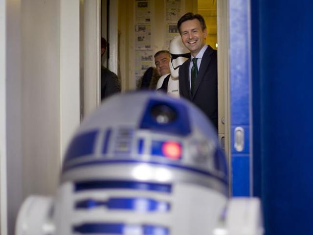 White House Press secretary Josh Earnest smiles as he watches R2D2 interact with members of the media during a surprise visit to the Brady Press Briefing Room of the White House. Star Wars movie characters will greet children of Gold Star families who are attending a special screening of Star Wars The Force Awakens at the White House Family Theater. (AP)