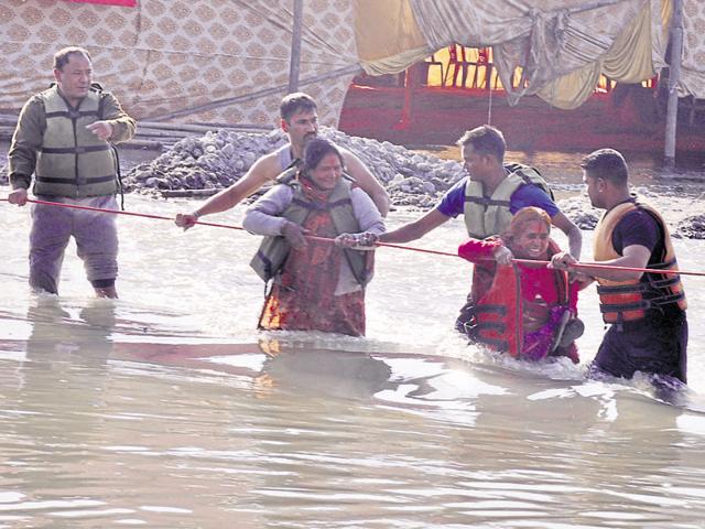 Police personnel rescue people after the water level rose suddenly in the Ganga in Rishikesh on Friday.(HT photo)