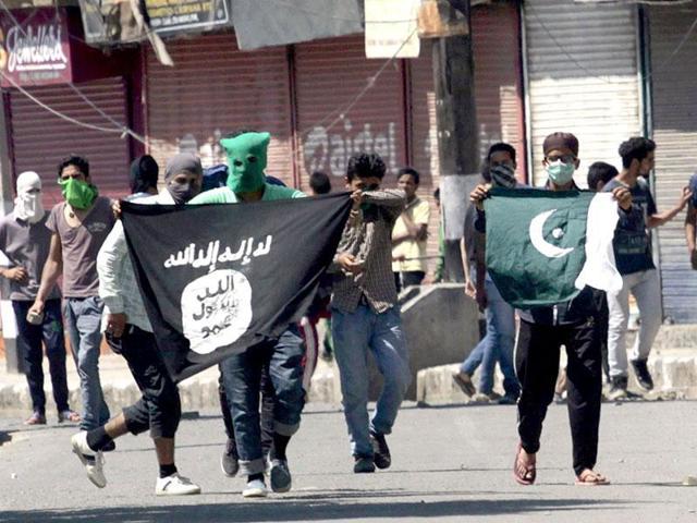 File photo of Kashmiri protesters displaying the flags of IS and Pakistan flag during a protest in Srinagar. Successive governments in the troubled region seem curiously averse to trying to win over the more aggressive elements in the state.(HT Photo)