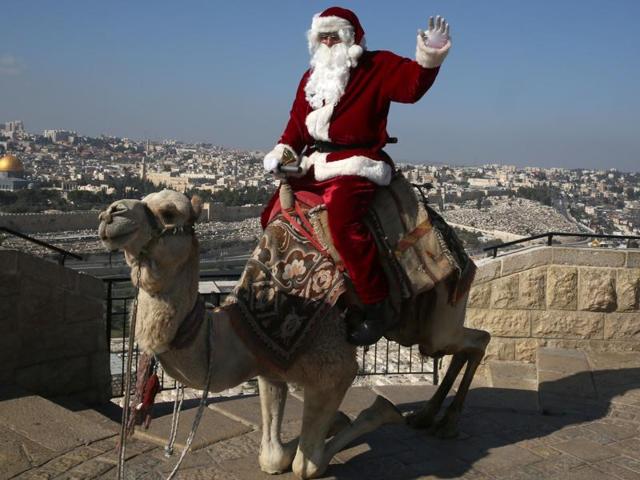 A Palestinian dressed up as Santa Claus rings a bell as he sits on a camel at Mt. Olives back-dropped by Jerusalem's Old City skyline. (AFP) A Palestinian dressed up as Santa Claus rings a bell as he sits on a camel at Mt. Olives back-dropped by Jerusalem's Old City skyline. (AFP)