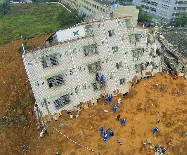 Rescue workers climb a ladder and onto a damaged building after the landslide hit an industrial park in Shenzhen. (Reuters photo)