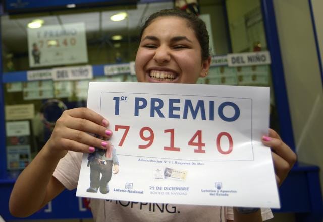 Winner Imanes Naamane celebrates as she holds a placard showing the first prize winning number, 79140, of Spain's Christmas Lottery "El Gordo" (The Fat One) at a lottery shop where the number was sold in Roquetas de Mar. (REUTERS)