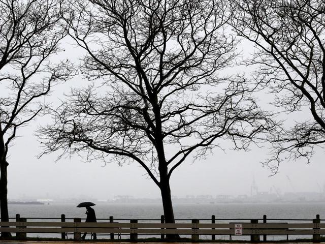 A man shelters himself from light rain with an umbrella in Jersey City. A weather pattern partly linked with El Nino has turned winter upside-down across the US.(AP photo)