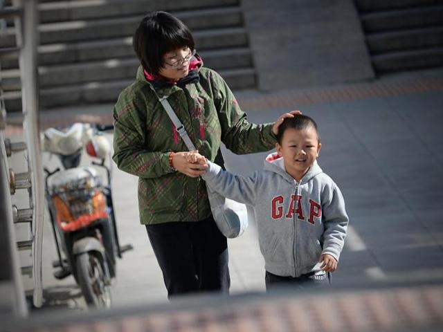 A woman takes a child's hand as they walk through an underpass in Beijing on October 30, 2015. China officially ended its one child policy on Sunday, December 27, 2015.(AFP) A woman takes a child's hand as they walk through an underpass in Beijing on October 30, 2015. China officially ended its one child policy on Sunday, December 27, 2015.(AFP)