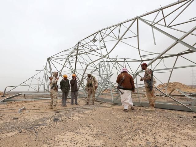 Soldiers loyal to Yemen's government and members of an engineering team stand next to destroyed transmission towers during a search for landmines left by the Houthi rebels in the Mas area on Saturday.(Reuters)