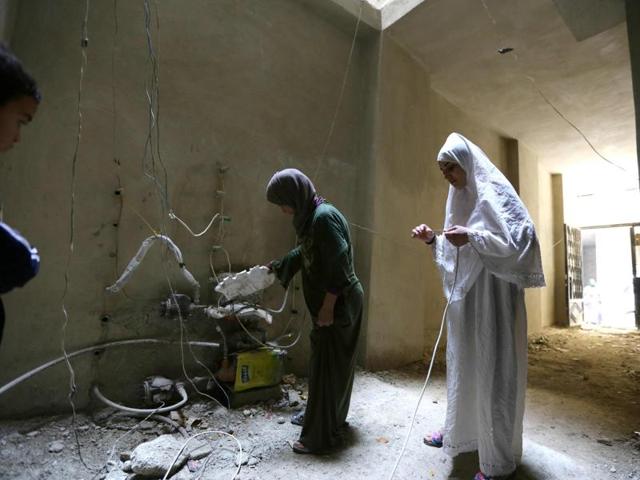 Relatives of Syrian Umm Walid check wires in an unfinished building where the family lives in the Daf al-Sakhr neighbourhood of Jaramana on the outskirts of the Syrian capital Damascus.(AFP) Relatives of Syrian Umm Walid check wires in an unfinished building where the family lives in the Daf al-Sakhr neighbourhood of Jaramana on the outskirts of the Syrian capital Damascus.(AFP)