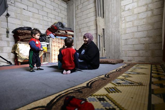 Syrian Umm Walid, 52, plays with her grandchildren in a room of an unfinished building where she lives with her five children and their families. (AFP) Syrian Umm Walid, 52, plays with her grandchildren in a room of an unfinished building where she lives with her five children and their families. (AFP)