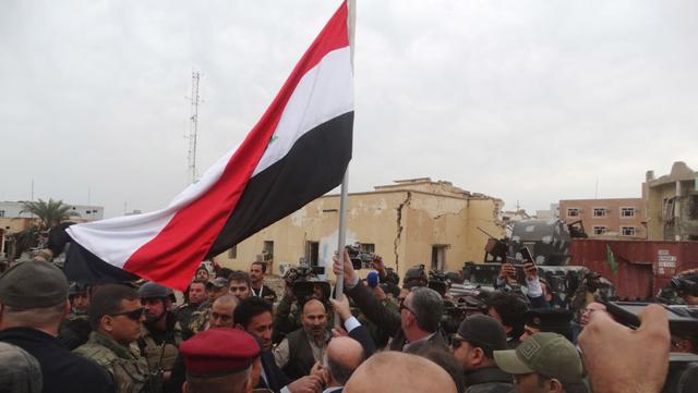 Iraqi Prime Minister Haider al-Abadi (C, back to camera) holds an Iraqi flag in the city of Ramadi. (Reuters) Iraqi Prime Minister Haider al-Abadi (C, back to camera) holds an Iraqi flag in the city of Ramadi. (Reuters)