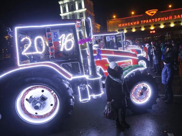 A woman poses for a photo next to tractors of Minsk Tractor Plant decorated to mark the upcoming New Year celebrations during a show in Minsk, Belarus. (AP Photo/Sergei Grits)