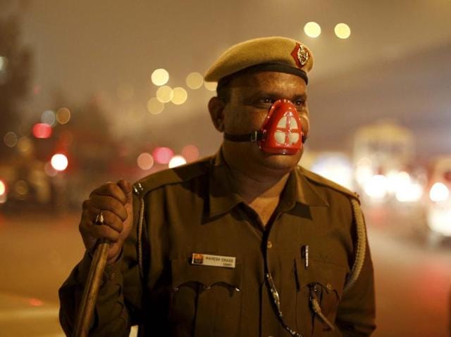 A Delhi Police constable with his face covered by a protective mask stands vigil at Anand Vihar . (Ravi Choudhary/Hindustan Times)