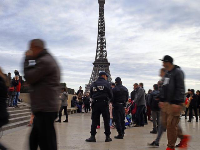 French Police officers stand guard amid tourists at Trocadero Plaza next to the Eiffel Tower in Paris. France strengthens security measures ahead of unusually tense New Year's eve celebrations in Paris after November attacks that left 130 dead and hundreds injured. (AP Photo/Francois Mori)